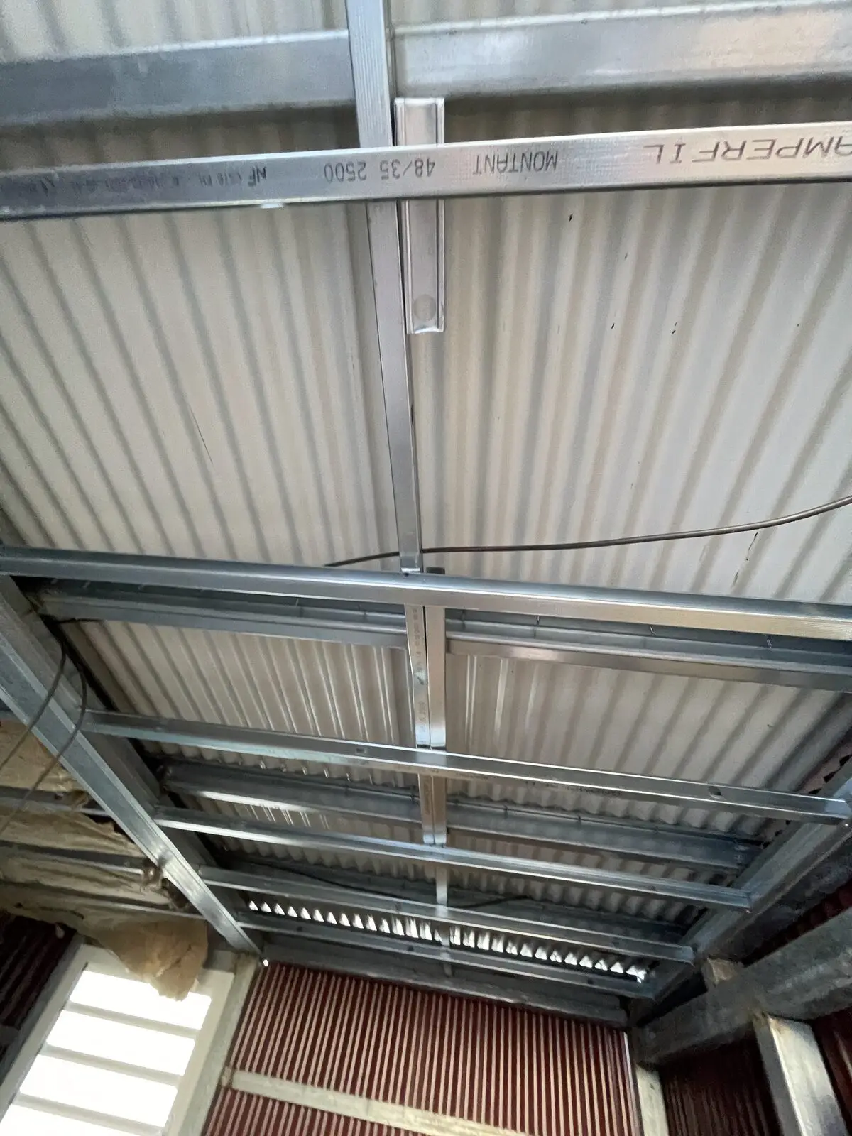 Ossature métallique de plafond suspendue sous la couverture, avant isolation